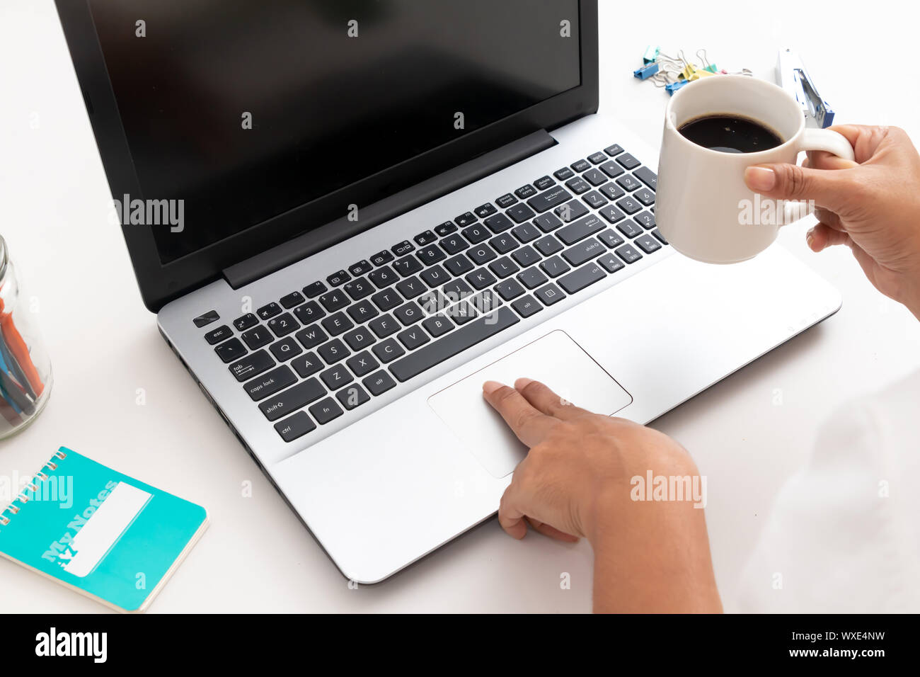 Les femmes qui travaillent sur un ordinateur portable et tenant une tasse de café sur un fond blanc Banque D'Images
