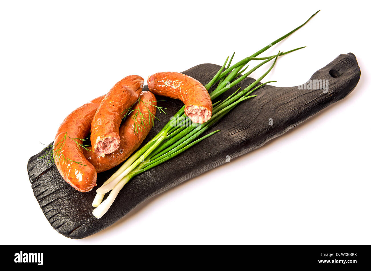 Saucisses grillées avec des oignons sur une carte sur un fond clair. Anneaux de saucisses juteuses dans une pile sur un fond blanc. Banque D'Images