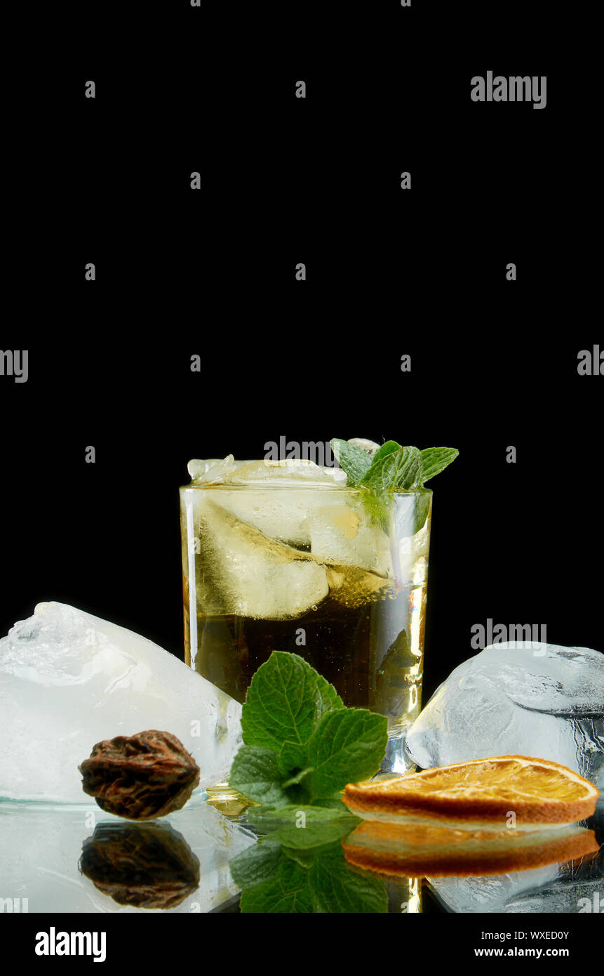 Cocktail sans alcool réfrigérés avec de la glace et des herbes fraîches orange sur fond noir Banque D'Images Cocktail sans alcool réfrigérés avec de la glace et des herbes fraîches orange sur fond noir Banque D'Images