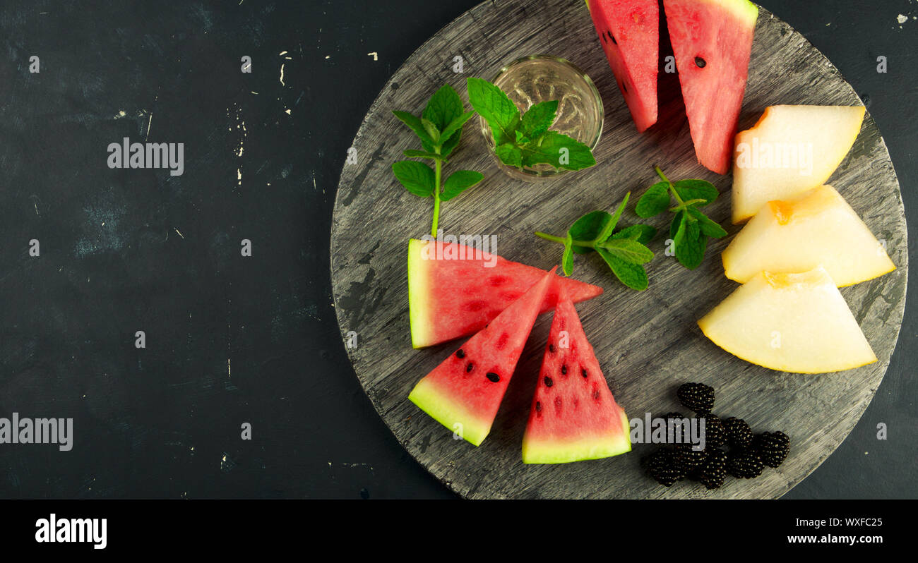 La pastèque MELON ET MENTHE BLACKBERRY SUR L'ARRIÈRE-PLAN. Trois MORCEAUX DE PASTÈQUE MELON mûr juteux avec des Mûres Mûres MINT Banque D'Images