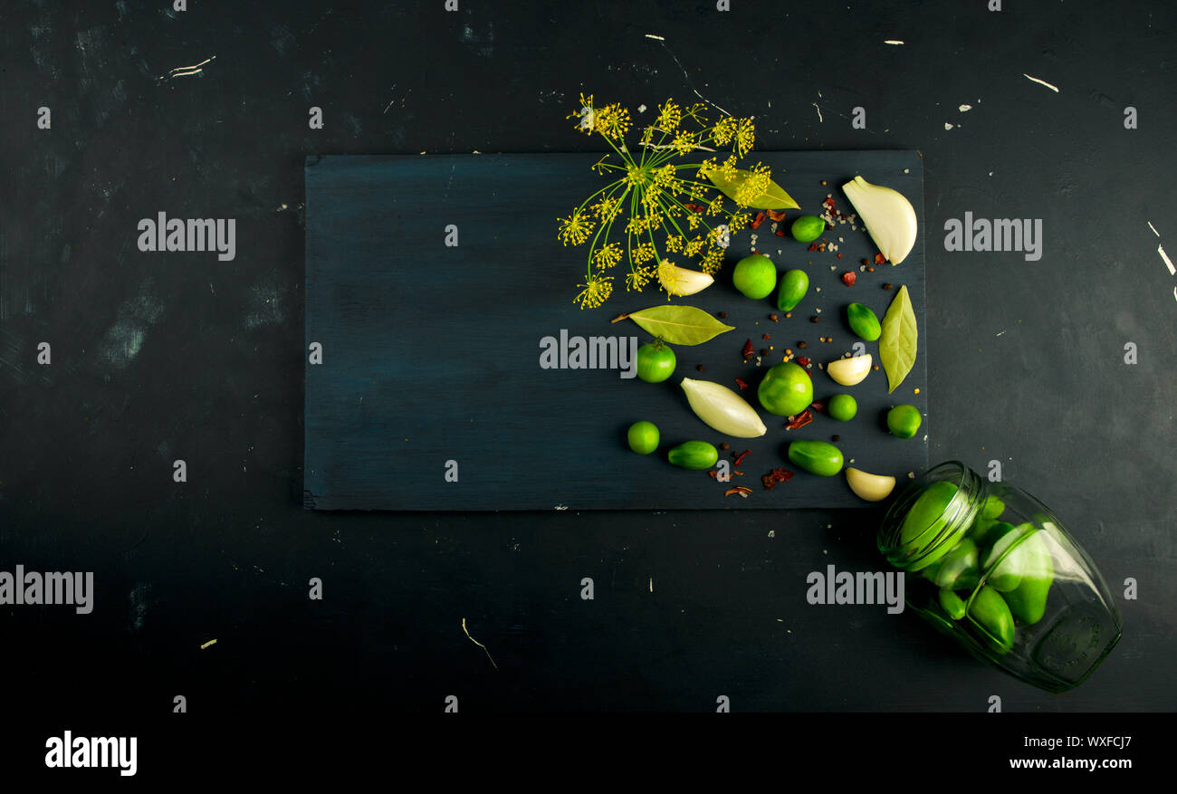 Tomates LÉGUMES ET ÉPICES AU CONSEIL. L'AIL ANETH TOMATES OIGNONS ÉPICES SUR UNE PLANCHE EN BOIS FONCÉ SUR UN SURFACE DE PIERRE Banque D'Images