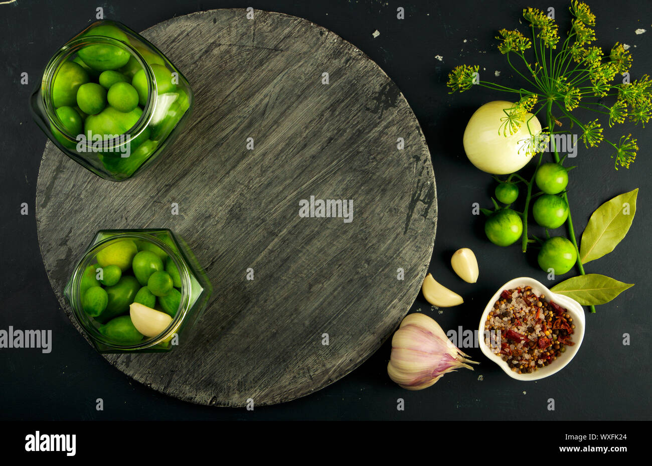 Tomates LÉGUMES ET ÉPICES AU CONSEIL. L'AIL ANETH TOMATES OIGNONS ÉPICES SUR PLANCHE EN BOIS GRIS SUR UNE SURFACE EN PIERRE posée. Banque D'Images