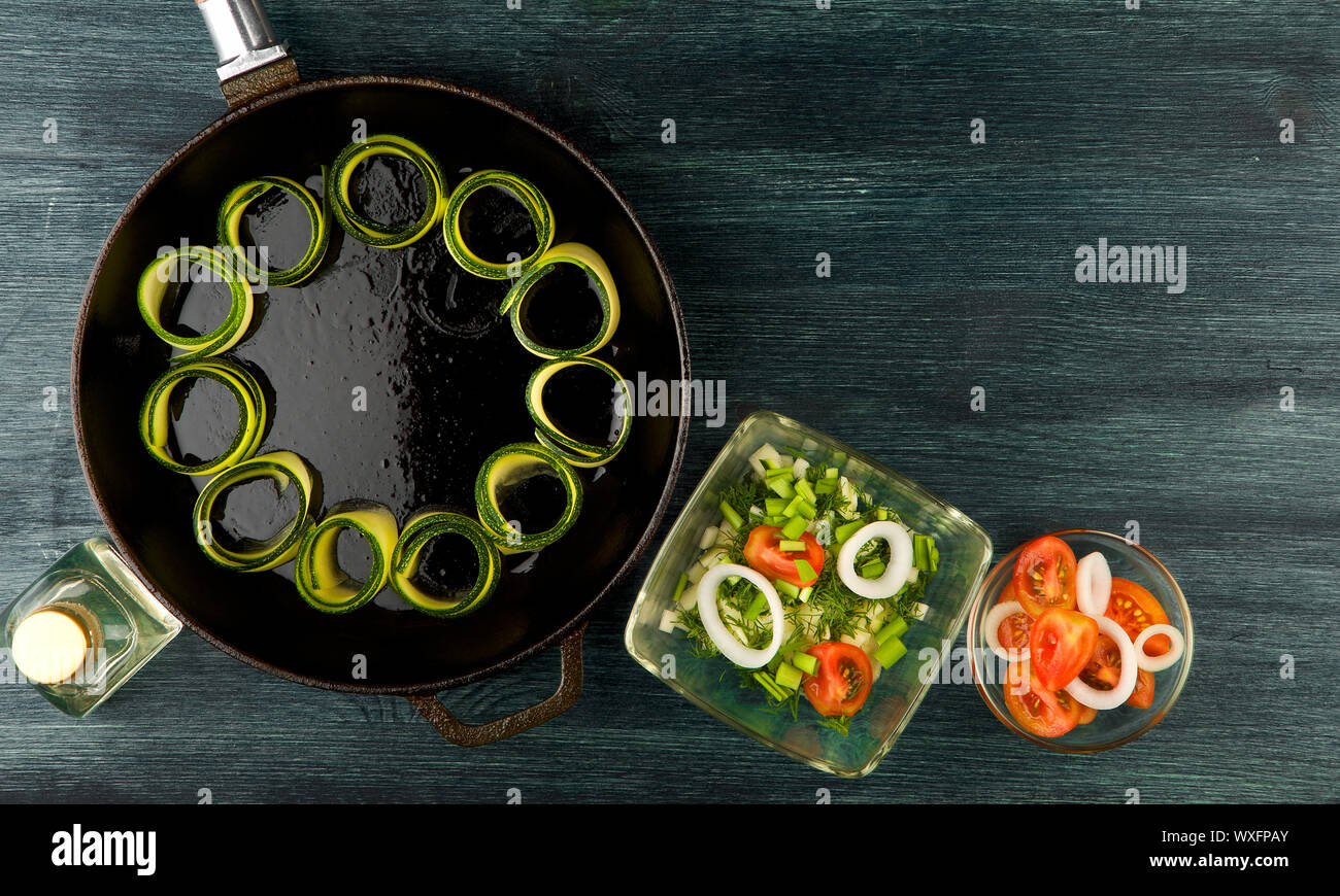 La courgette dans l'arrière-plan. Les jeunes courgettes en rondelles frites dans une casserole sur un fond sombre. La vue du sommet. Copy space Banque D'Images