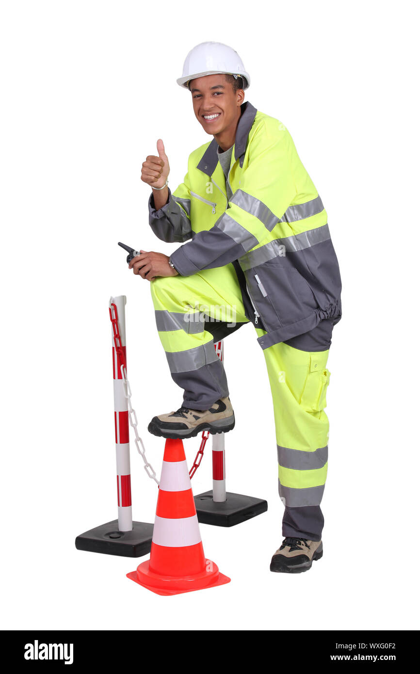 L'homme en bleu de travail haute visibilité avec un cône de trafic et d'obstacles Banque D'Images