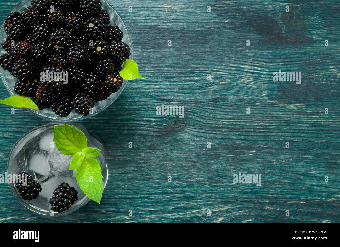 Blackberry frais. Blackberry juteux dans un bol et un verre d'eau glacée aux fruits rouges sur une table en bois. Vue de dessus. Copie Banque D'Images