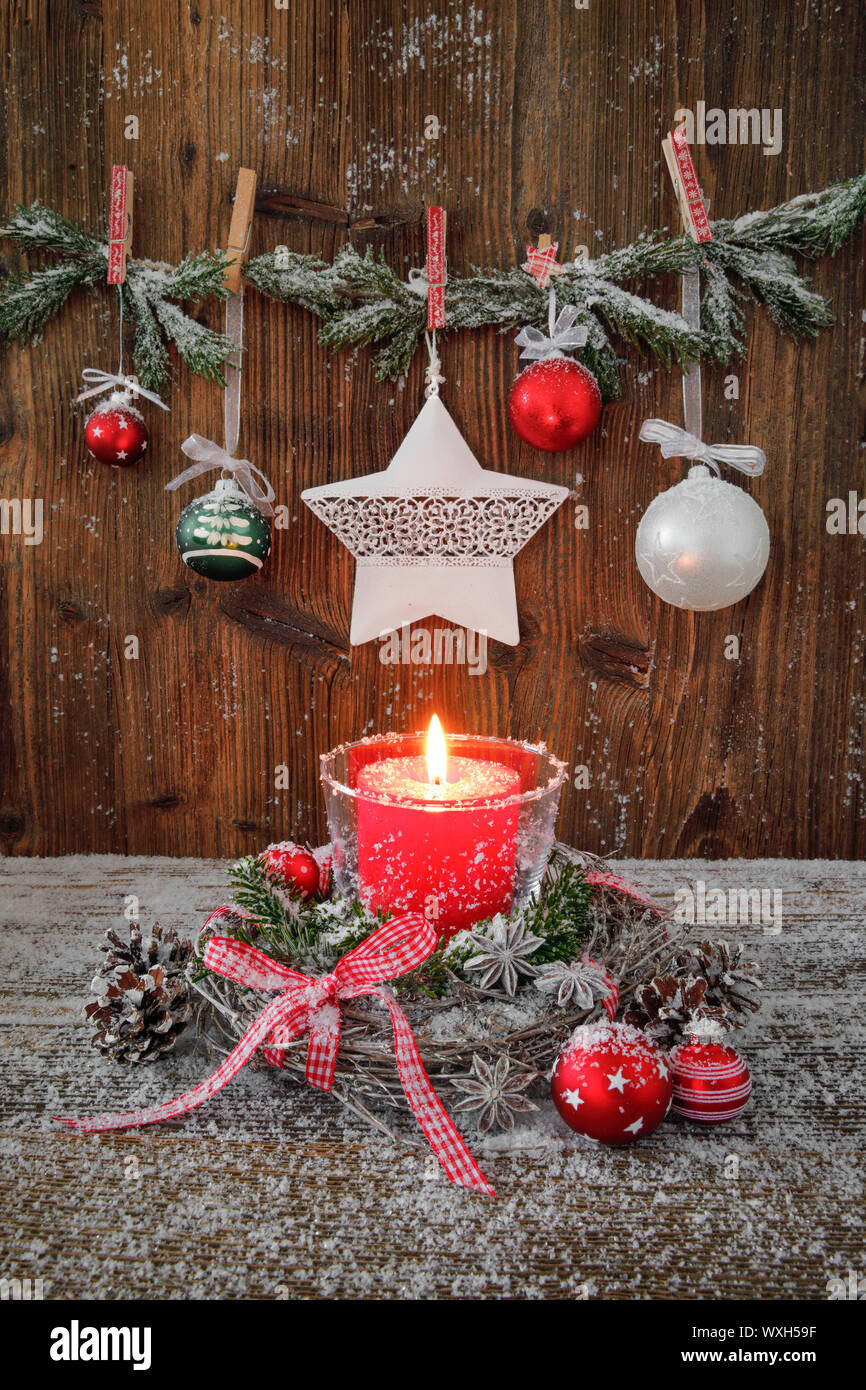 Naturelle décoration de Noël : une bougie rouge dans une lanterne entouré d'une couronne de brindilles sur une planche en bois. Banque D'Images