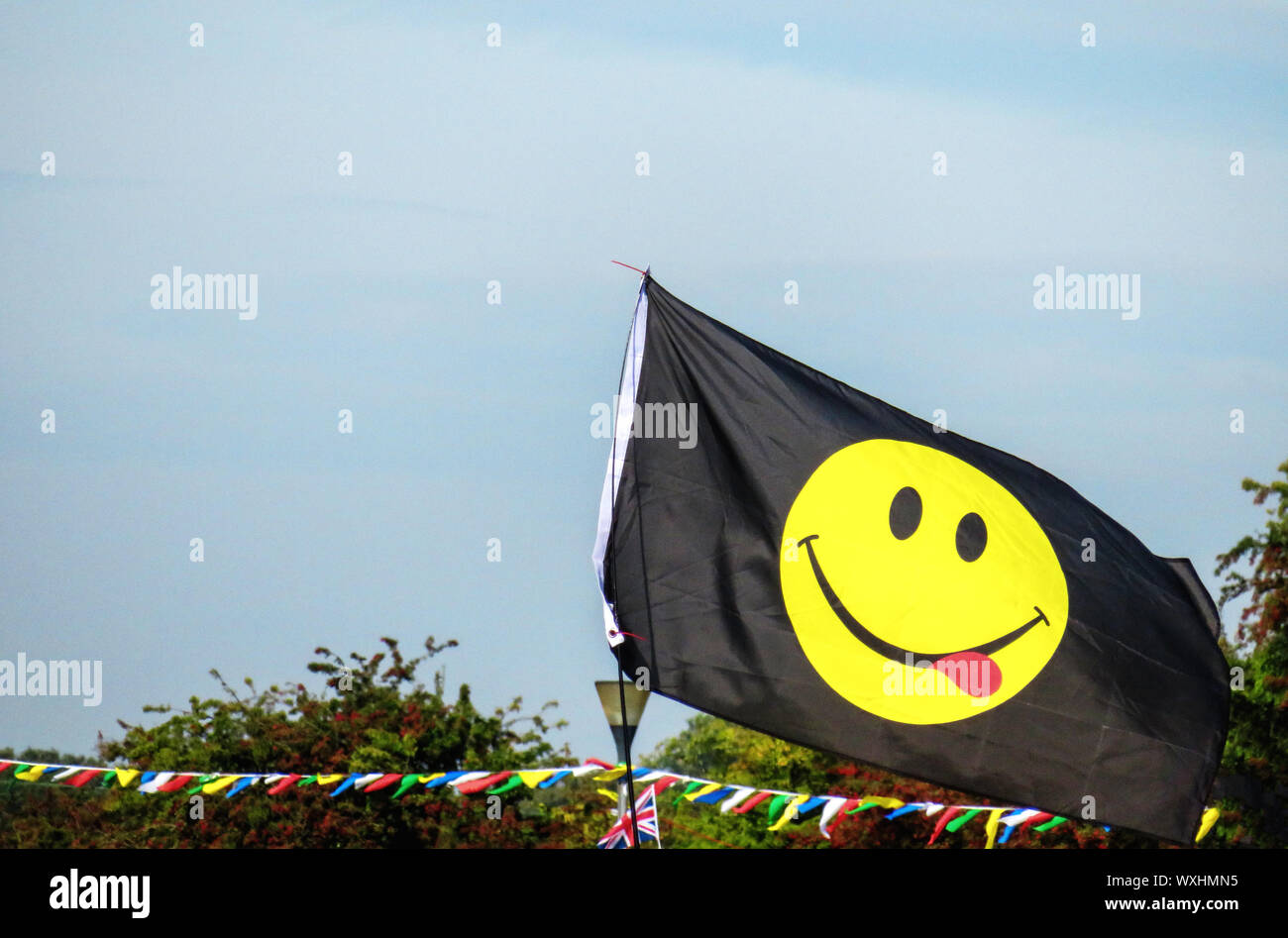 Visage souriant jaune sur l'emoji un drapeau noir Banque D'Images