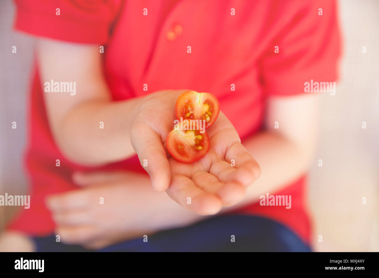 Garçon tenant une moitié de tomate cerise Banque D'Images