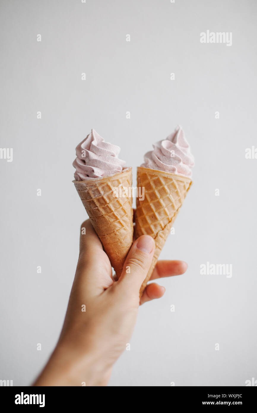 Woman's hand holding deux cônes alvéolés avec crème fouettée Banque D'Images