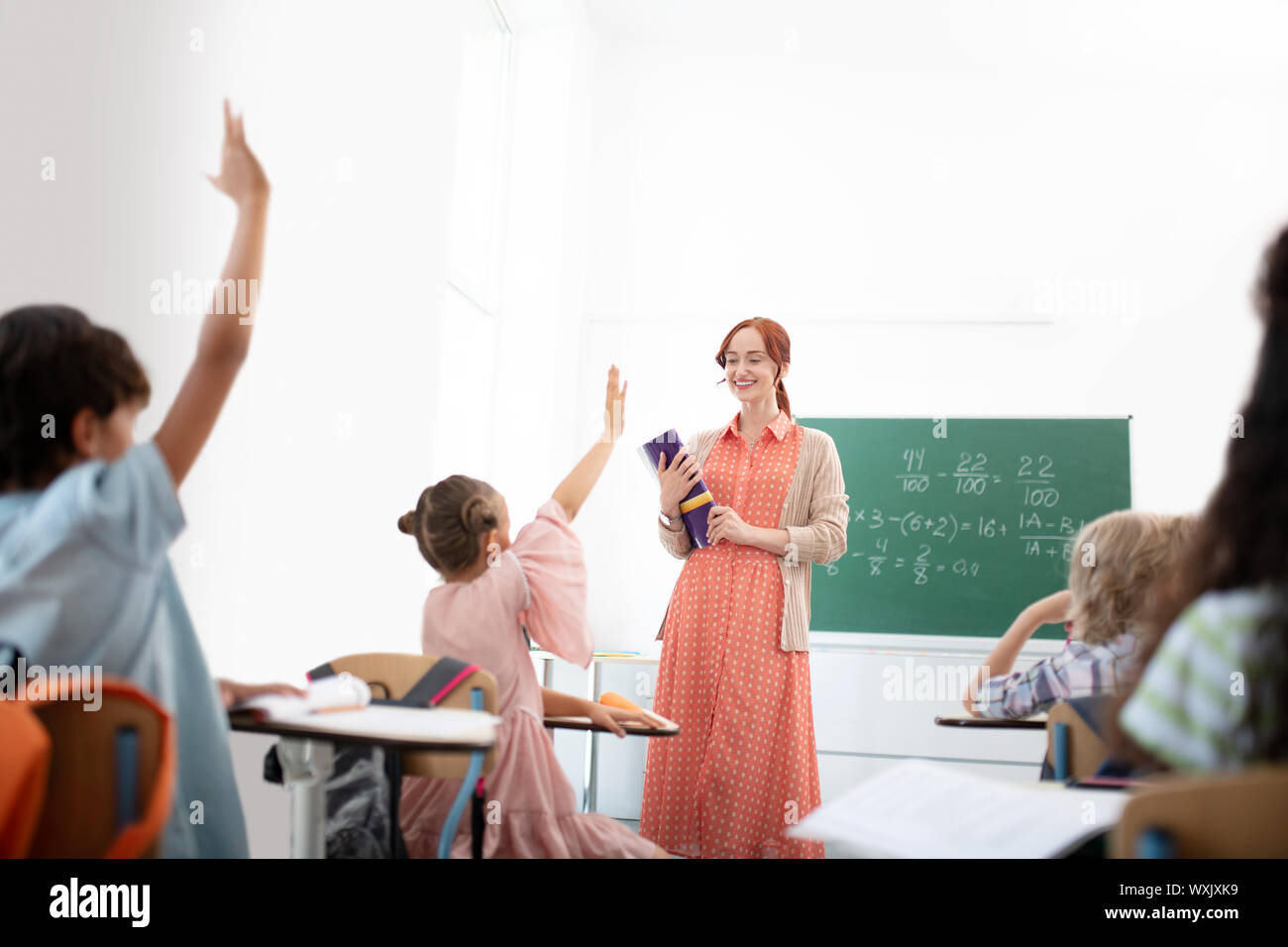 Red-haired teacher smiling tout en se sentant satisfaits de ses élèves Banque D'Images