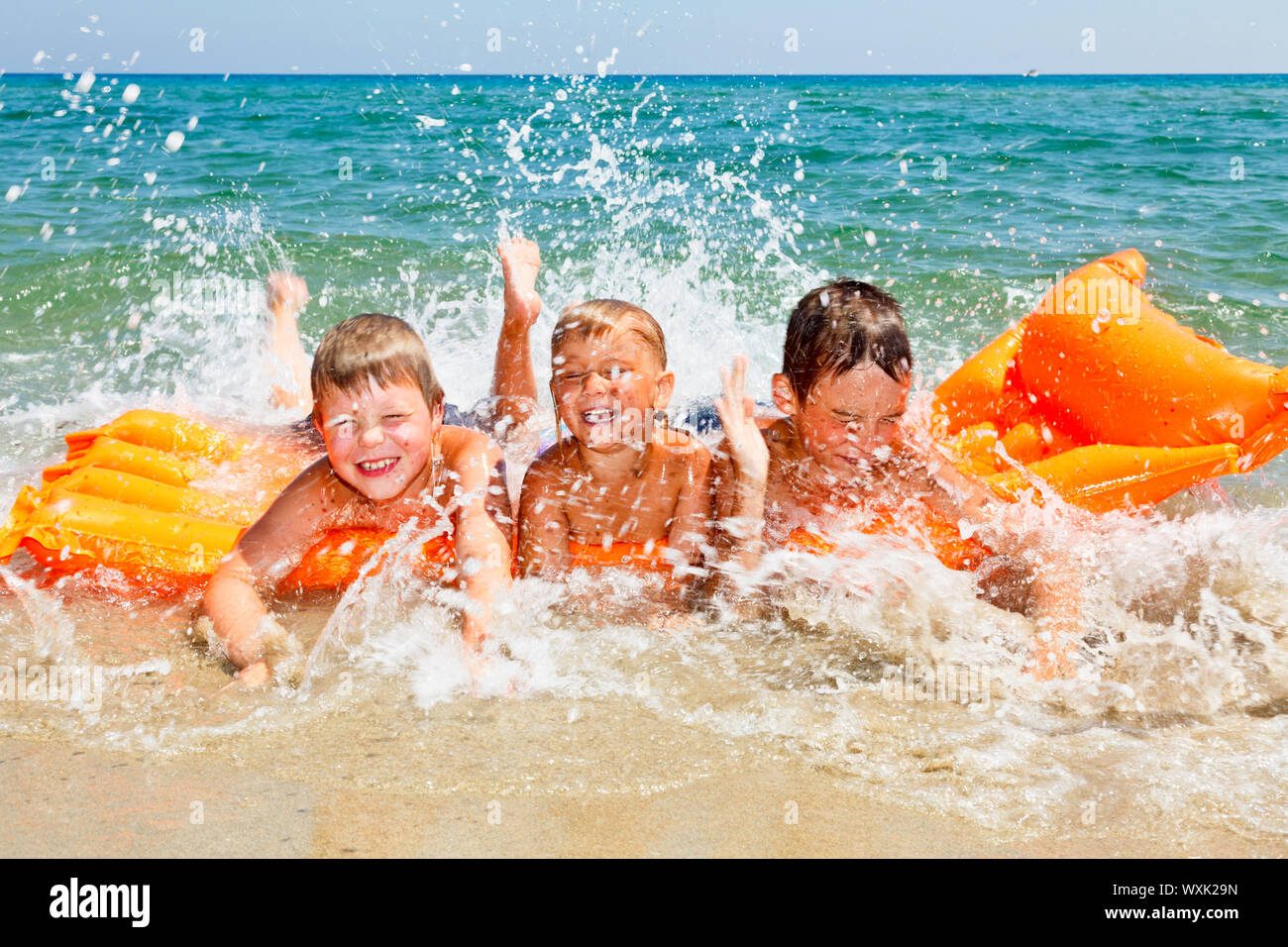 Trois enfants aux projections d'eau sur une plage Banque D'Images