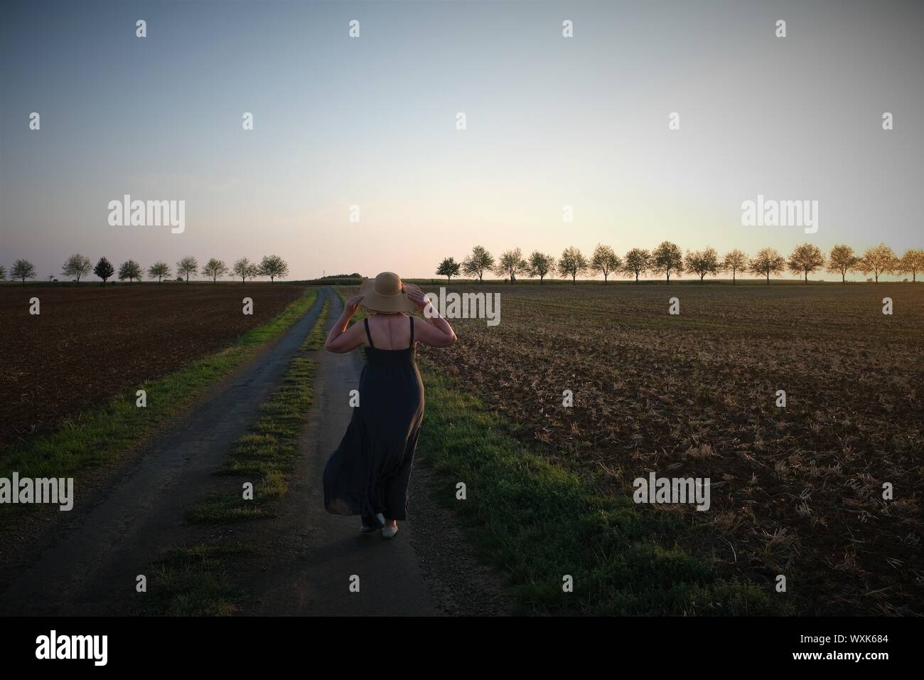 Femme marchant le long d'une route rurale, Deux-Sèvres, Nouvelle Aquitaine, France Banque D'Images