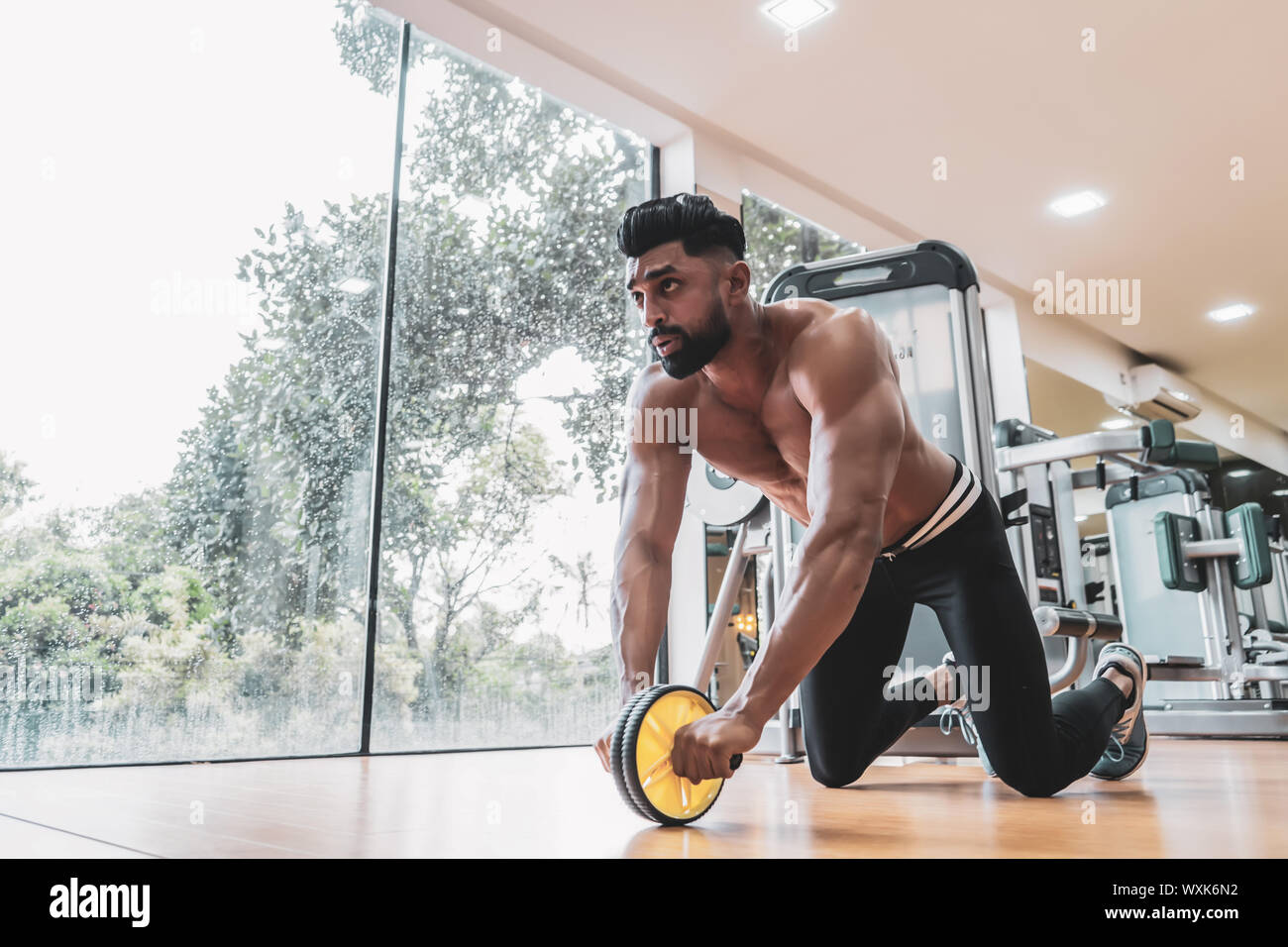 Sportive de l'athlète homme faire de l'exercice de l'abs roue de rouleau pour renforcer ses muscles abdominaux en salle de sport. Banque D'Images