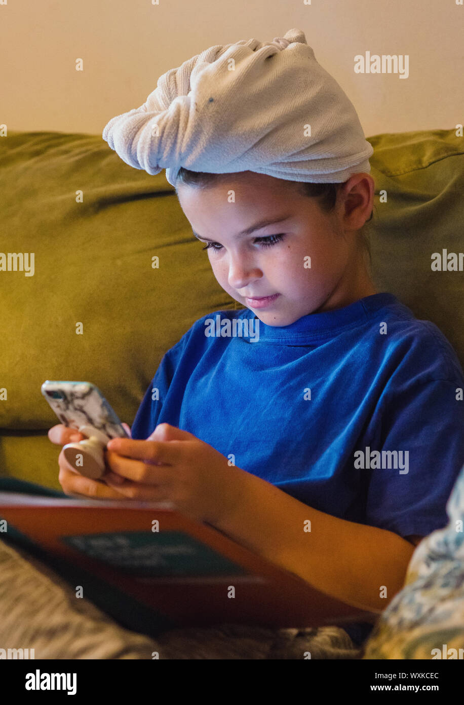 Fille avec une serviette sur la tête en regardant son téléphone portable Banque D'Images