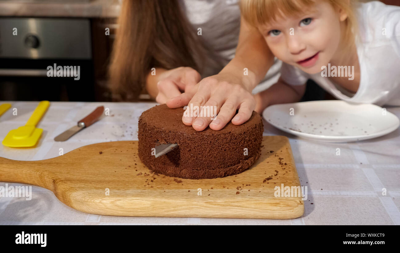 Portrait De Famille De Maman Et Les Filles Sont En Train De Preparer Le Gateau D Anniversaire Ensemble Maman Est Une Eponge Coupe Gateau A L Aide Du Couteau En Cuisine Photo Stock