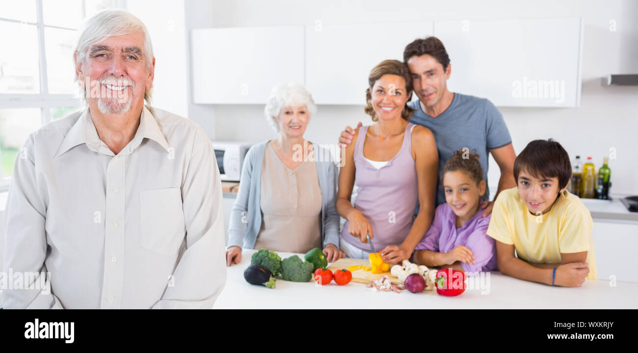 Grand-père debout par comptoir de la cuisine avec la famille derrière lui Banque D'Images