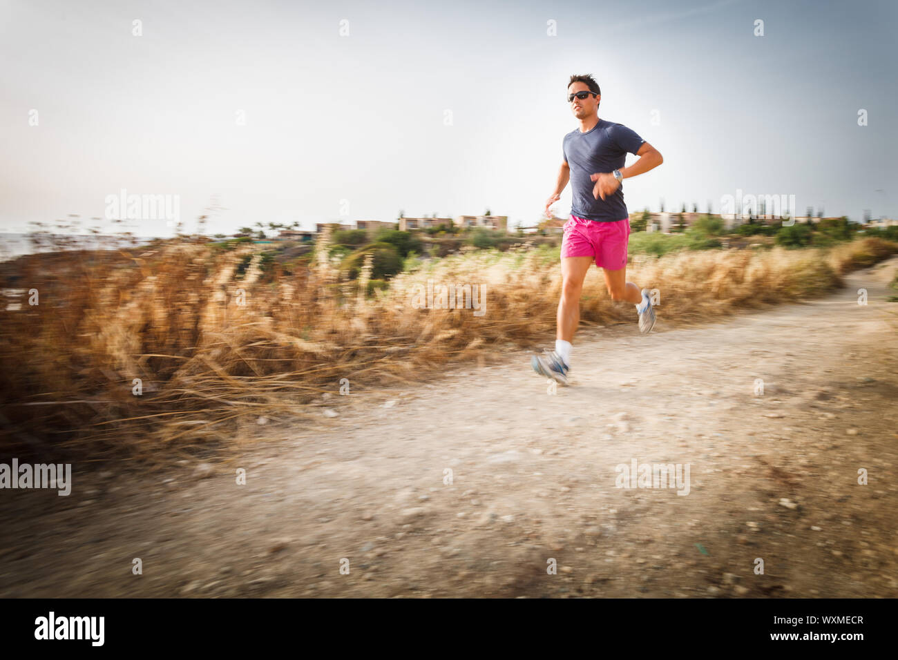 Jeune homme de race blanche s'exécutant sur un chemin mi-ombre sur un beau soir d'été, la formation pour le marathon (motion image floue) Banque D'Images