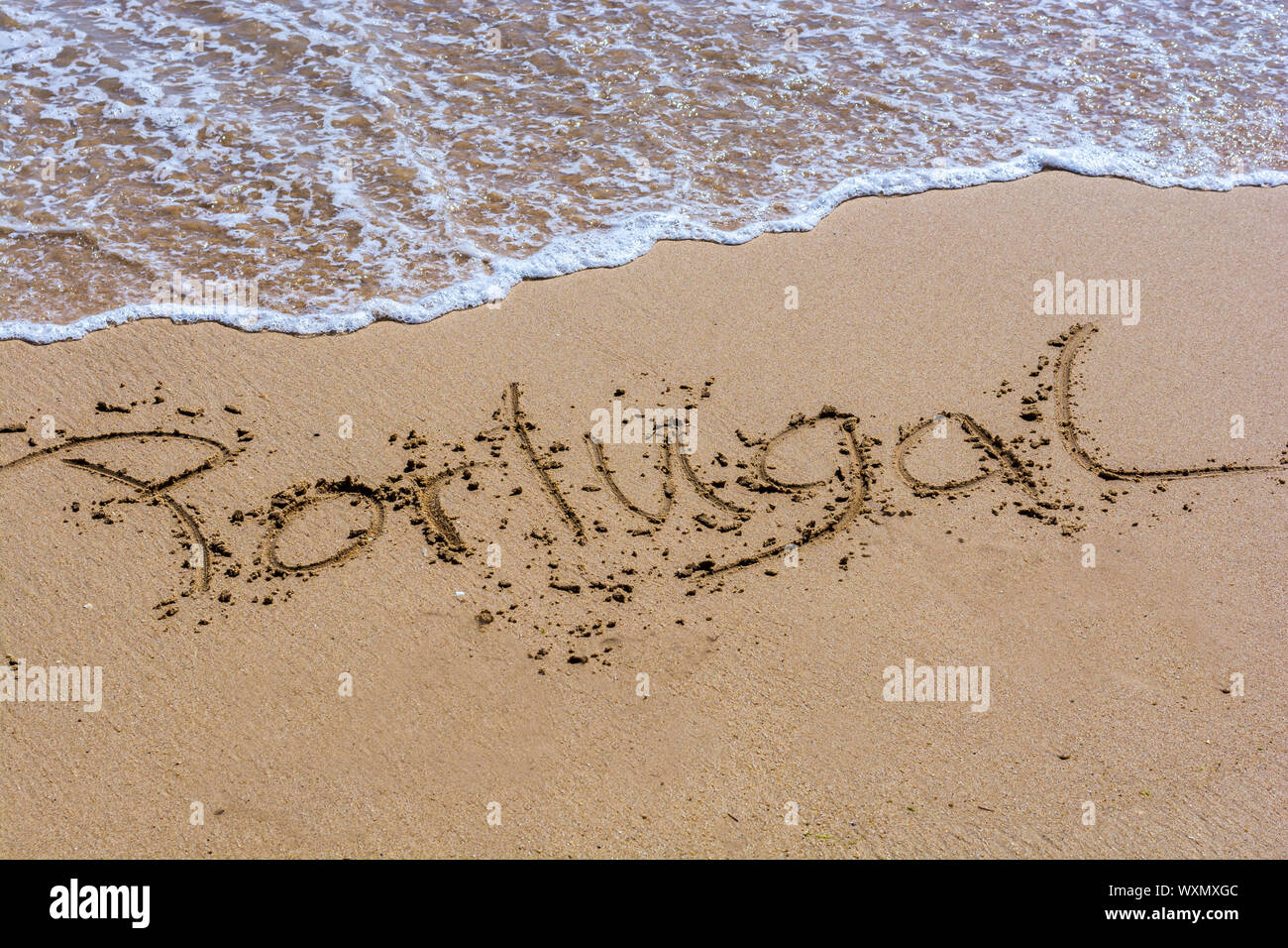 Le mot Portugal en langue allemande écrite dans une plage de sable Banque D'Images