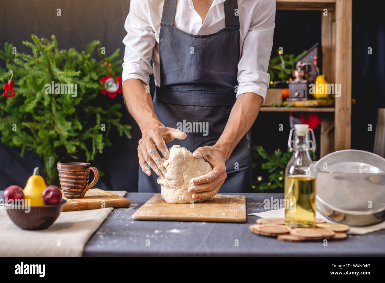 L'homme cuisine dans un tablier noir la pâte à pétrir avec ses mains
