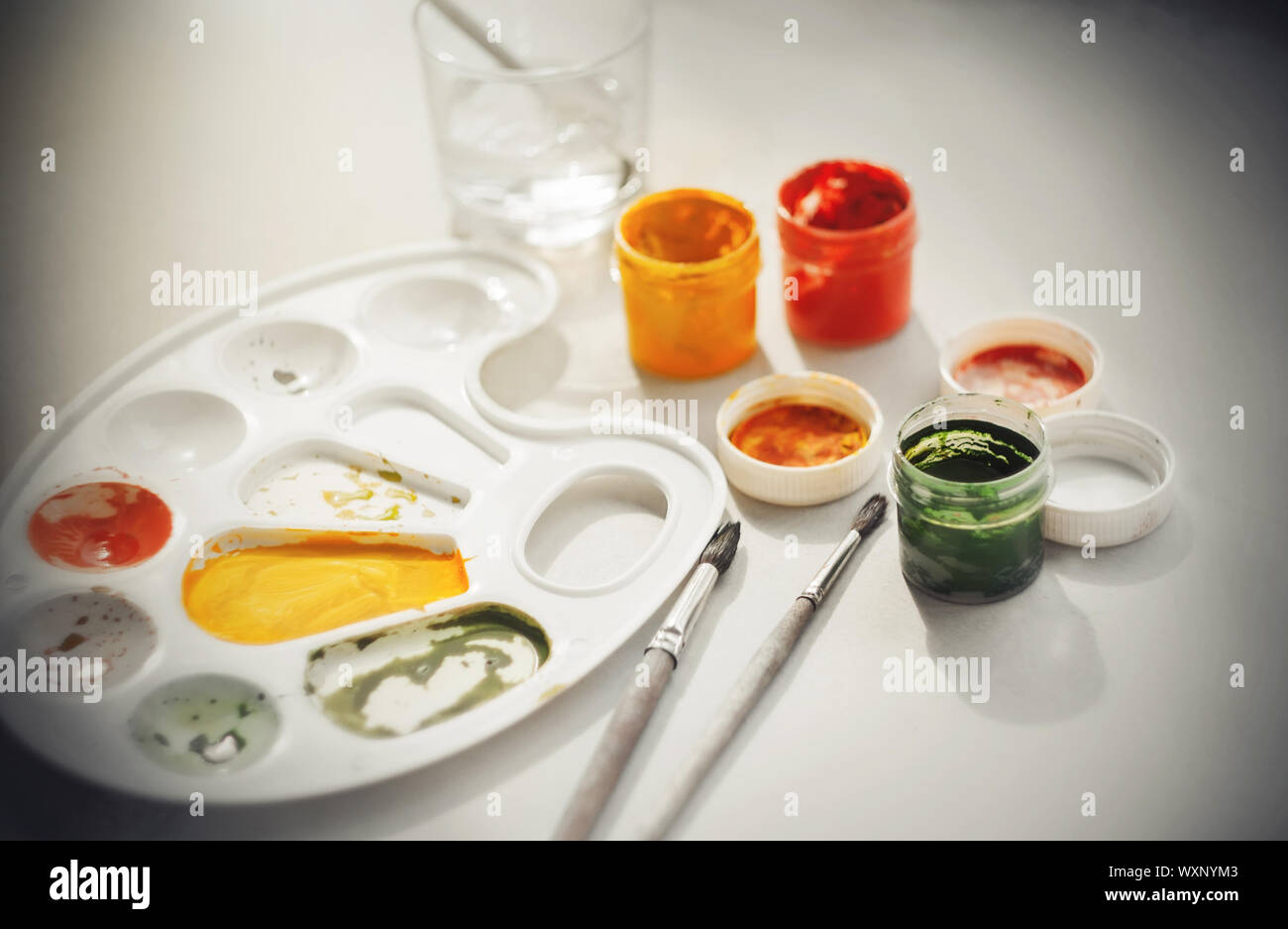 Le brillant des couleurs pures de gouache en pots et de la palette se démarquer par rapport au reste de la monde noir et blanc jusqu'à ce qu'ils diffèrent en cela de la peinture Banque D'Images