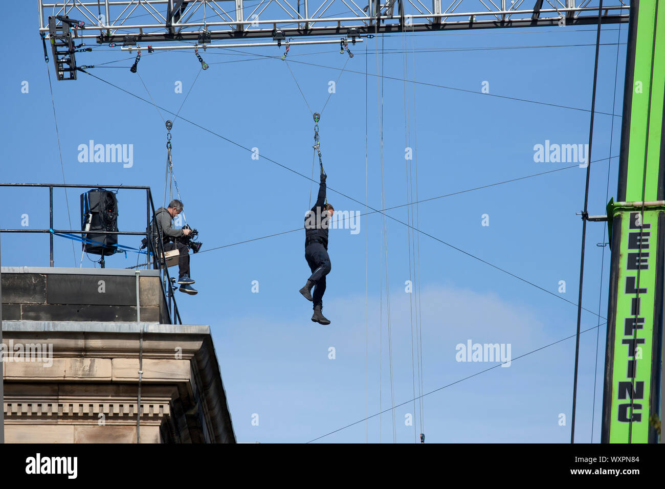 Les toits, West College Street, Édimbourg, Écosse, Royaume-Uni. 17 septembre 2019. Temps clair soleil et ciel bleu pour le tournage de "Fast and Furious 9', sur la photo, film cameraman et acteur cascadeur en suspension dans l'air d'un bras qu'ils fil zip sur la poulie avec une énorme grue, comme cette scène s'est poursuivie pour la deuxième journée, au-dessus du centre-ville rues. Banque D'Images