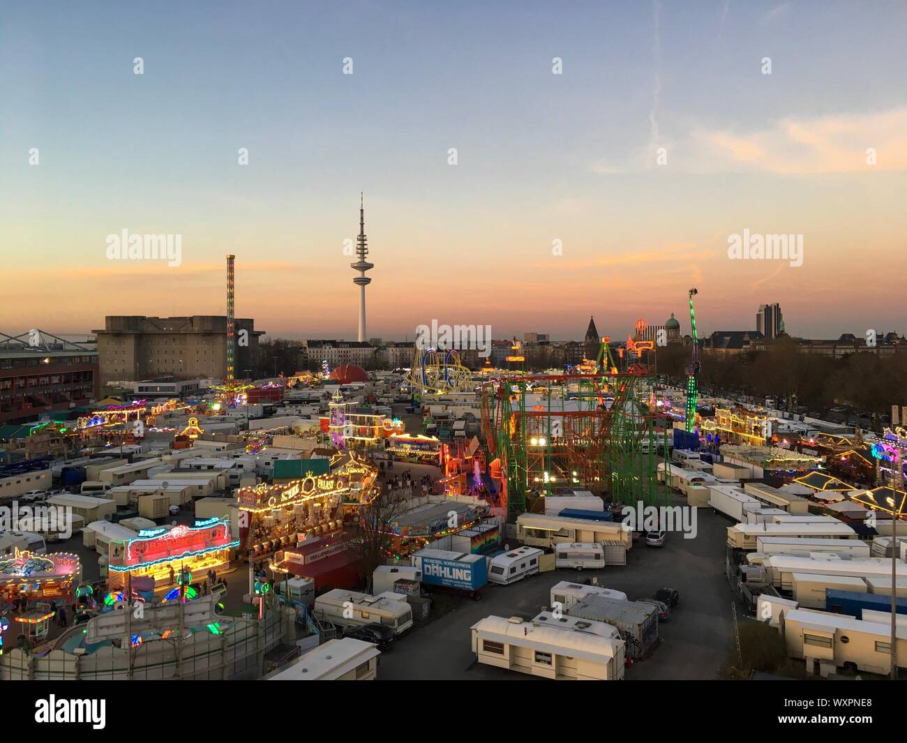 Hambourg - Mars 27, 2017 : Large Vue aérienne du grand Fun Fair 'Hamburger Dom' Avec montagnes russes, manèges de carnaval et Hambourg Skyline at Dusk Banque D'Images
