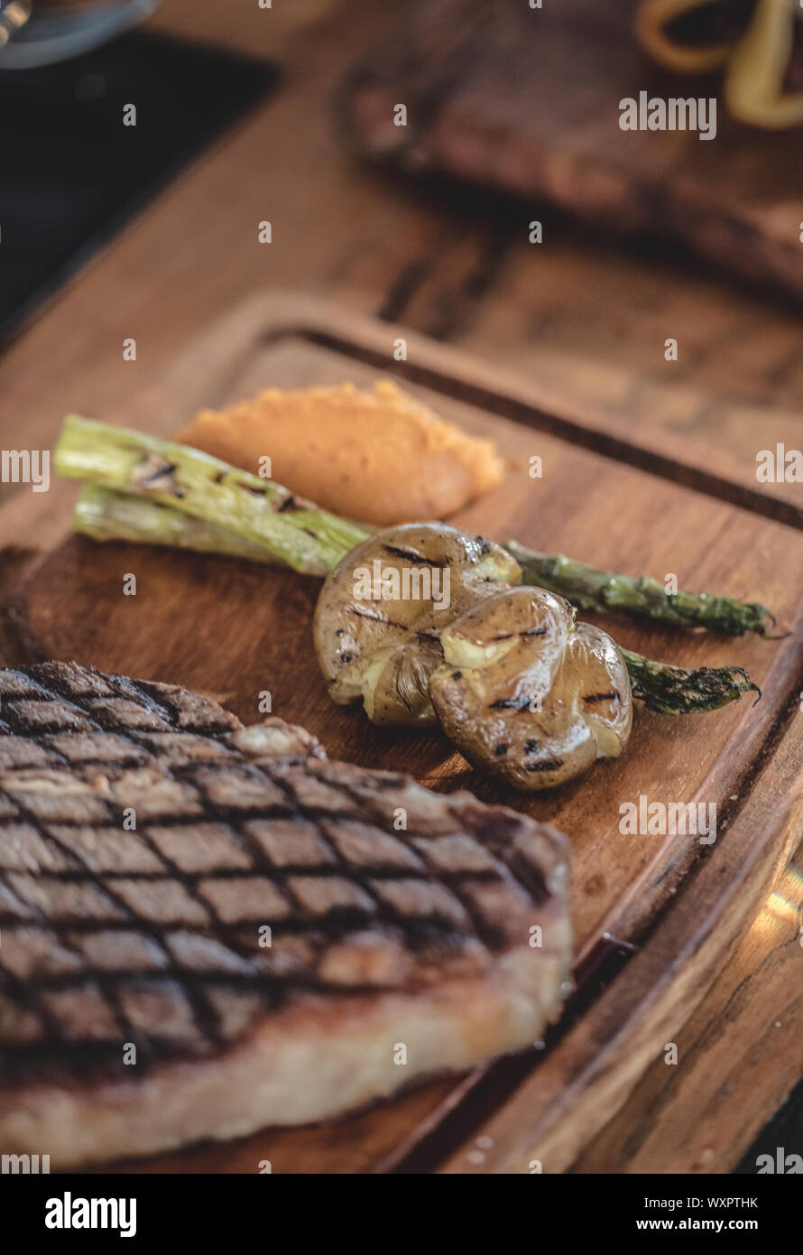 Barbecue steak de boeuf servi sur une assiette en bois, légumes grillés Banque D'Images