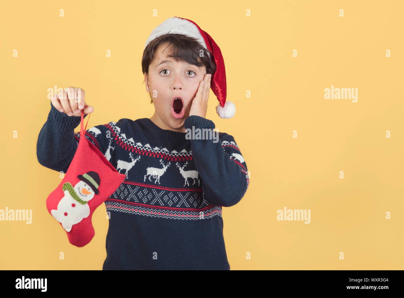 L'enfant surpris Wearing Christmas Santa Claus Hat sur fond jaune Banque D'Images