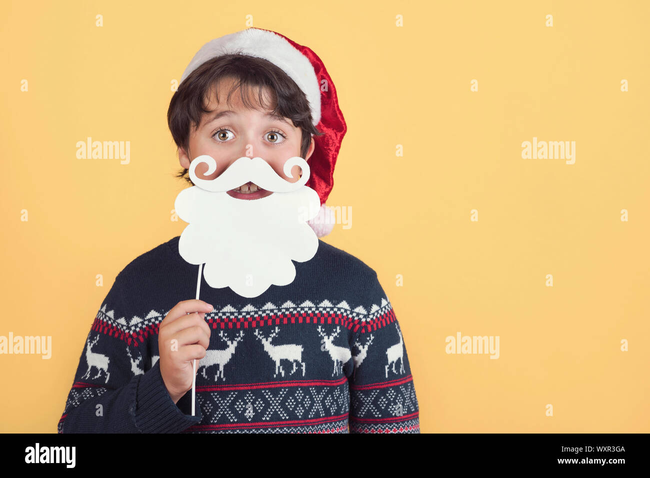 Child Wearing Christmas Santa Claus Hat et beard sur fond jaune Banque D'Images