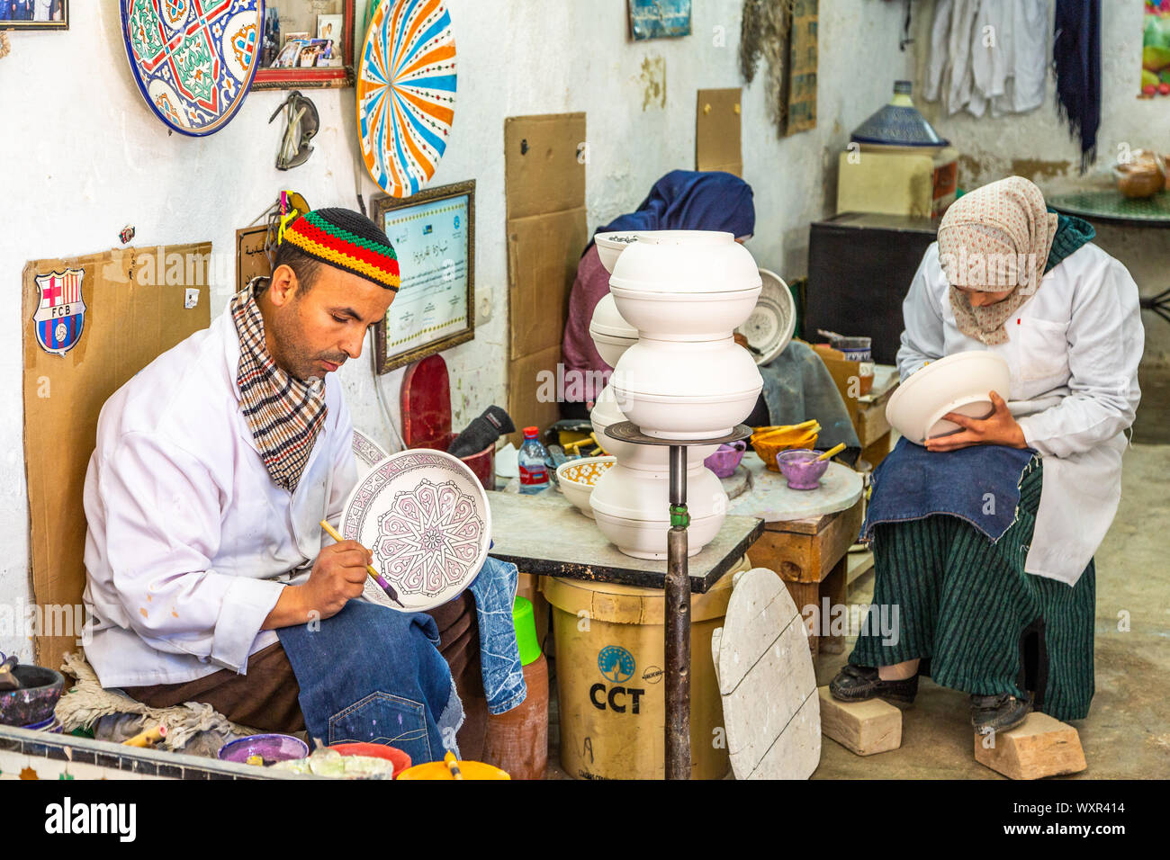 Les hommes et les femmes dans un atelier/usine de production de poterie marocaine peinte à la main, des bols, des plats internationaux dans des modèles et styles, Fès, Maroc Banque D'Images