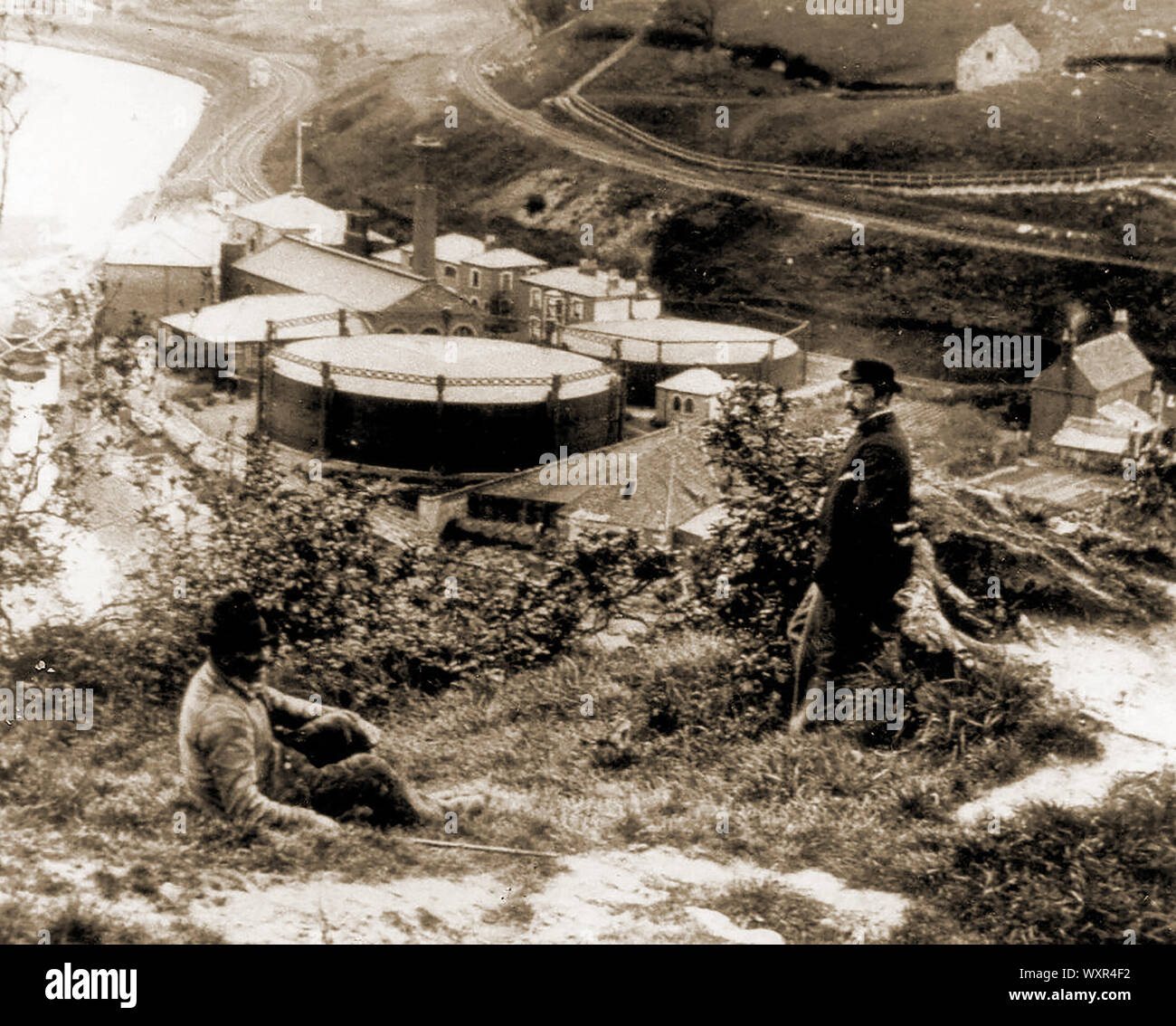 Une photo de l'ancien travaux gaz (aujourd'hui démoli) à Whityby North Yorkshire, Angleterre. La photo est prise à partir de la rive est de la rivière Esk qui allait plus tard être connecté à l'est par un viaduc ferroviaire d'être construit sur l'emplacement. Les lignes de chemin de fer de Whitby à Middlesbrough via la côte, et à Whitby à Middlesbrough via l'Esk Valley peut être vu en face des deux hommes. L'usine à l'abandon a été plus tard repris par site Fif Robinson qui y vivaient en utilisant des panneaux solaires pour fournir de l'électricité. Banque D'Images