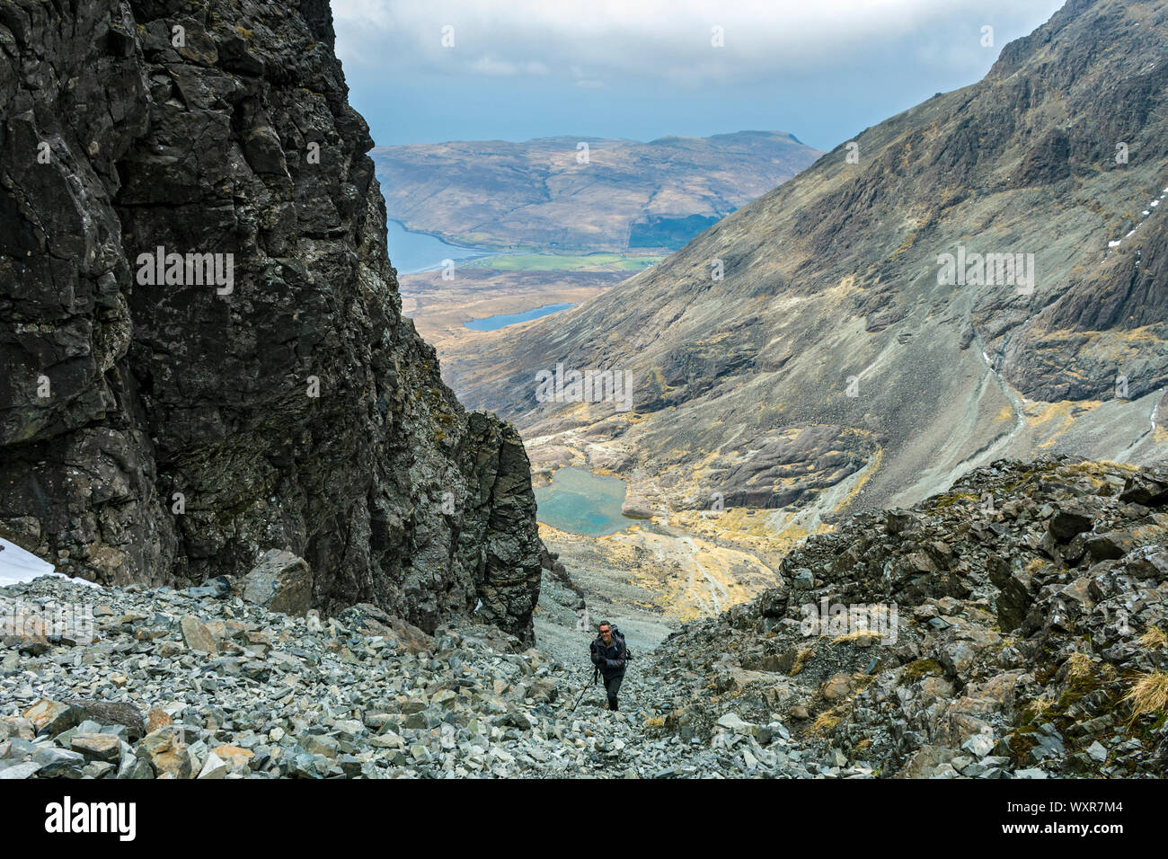 Un marcheur l'ascension de la grande pierre tirer au-dessus de Coire Lagan et Glen cassante. Dans les montagnes Cuillin, ont profité, Isle of Skye, Scotland, UK Banque D'Images