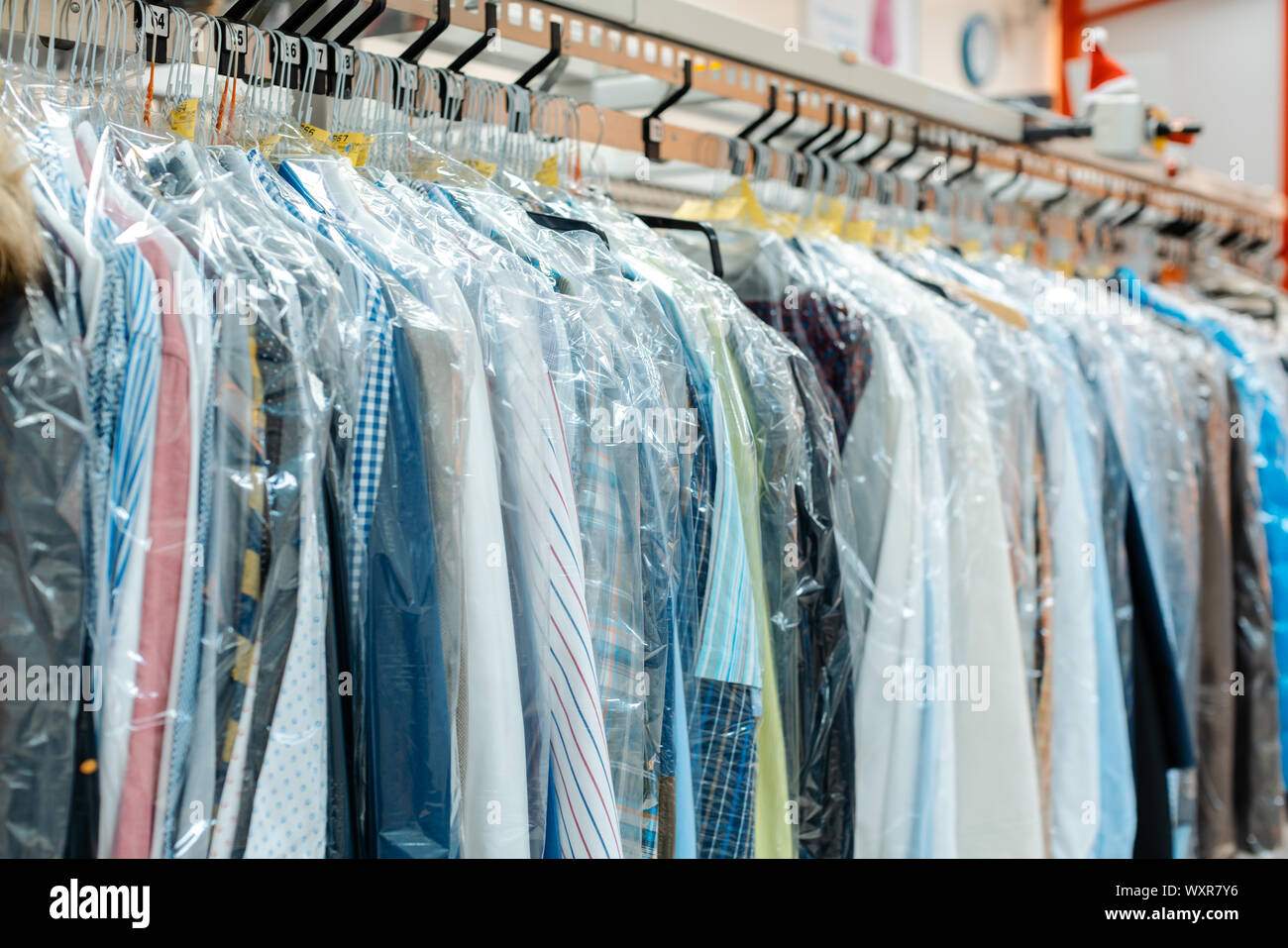Carousel de vêtements en attente de prise en charge par leurs propriétaires dans un service de nettoyage à sec boutique Banque D'Images