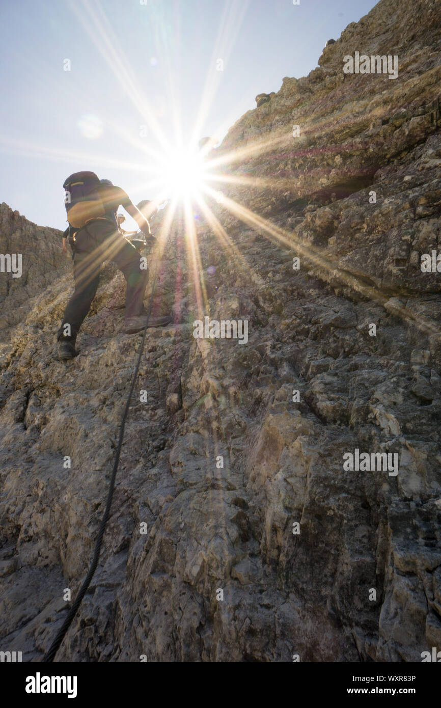 Groupe d'alpinistes sur un vertical via ferrata dans les Dolomites italiennes avec une star qui brille dans la lumière d'or Banque D'Images