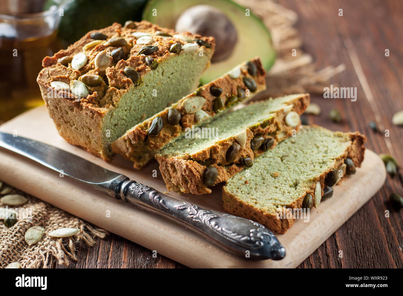 Avocsdo en tranches de pain sur une planche à découper en bois avec de l'avocat, l'huile et les graines de citrouille en arrière-plan Banque D'Images