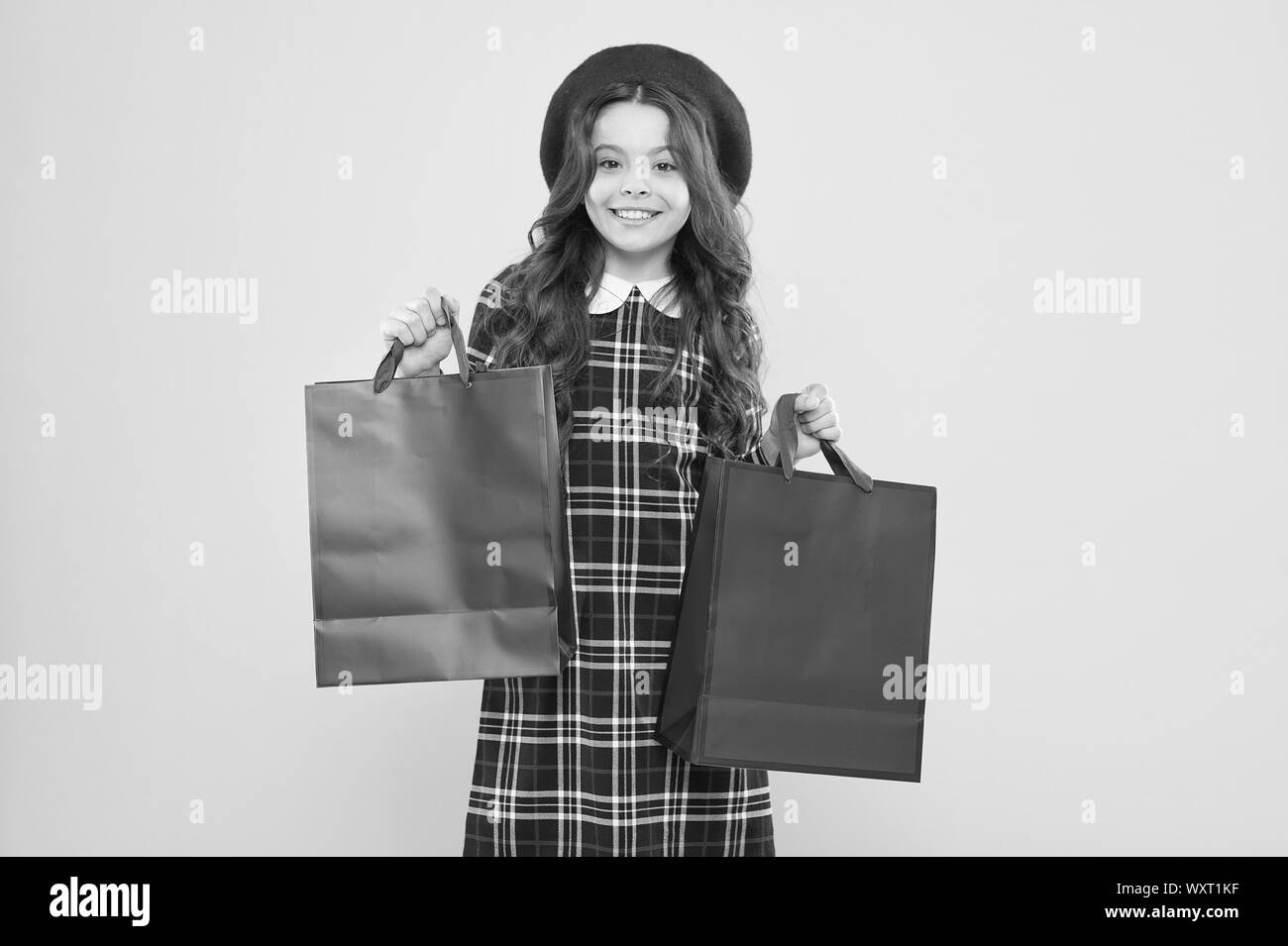 Petite fille au chapeau de style français. petite beauté accro. Maison de vacances présent. shopping. enfant accro du shopping online. enfant parisien sur fond jaune. bonne fille avec de longs cheveux bouclés en béret. Banque D'Images