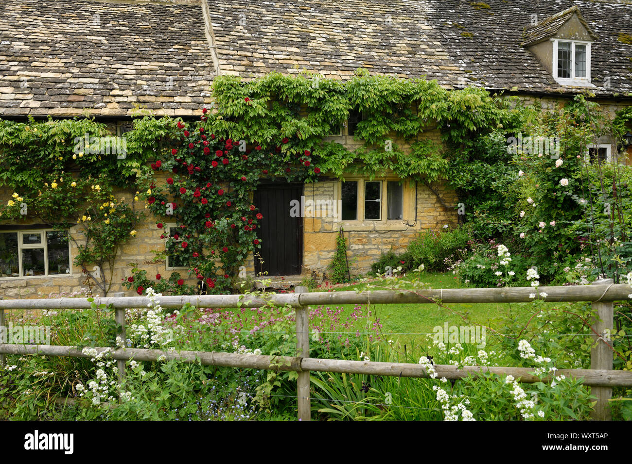 Chambre jaune avec des murs en calcaire de Cotswold et toiture en ardoise avec jardin de fleurs et de roses en Snowshill Gloucestershire Angleterre Banque D'Images