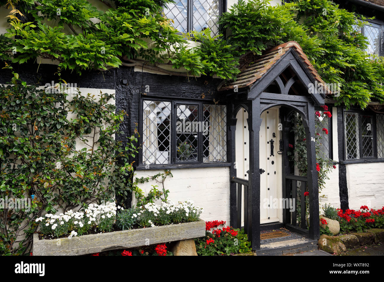 Plantes à fleurs sur fond noir et blanc de style Tudor cottage at Bridge End à Warwick sur la rivière Avon, Angleterre Banque D'Images