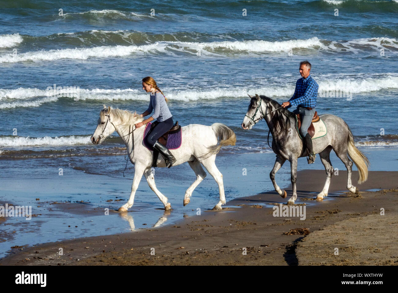 Couple de l'équitation sur une plage, littoral de la côte de l'Espagne Banque D'Images