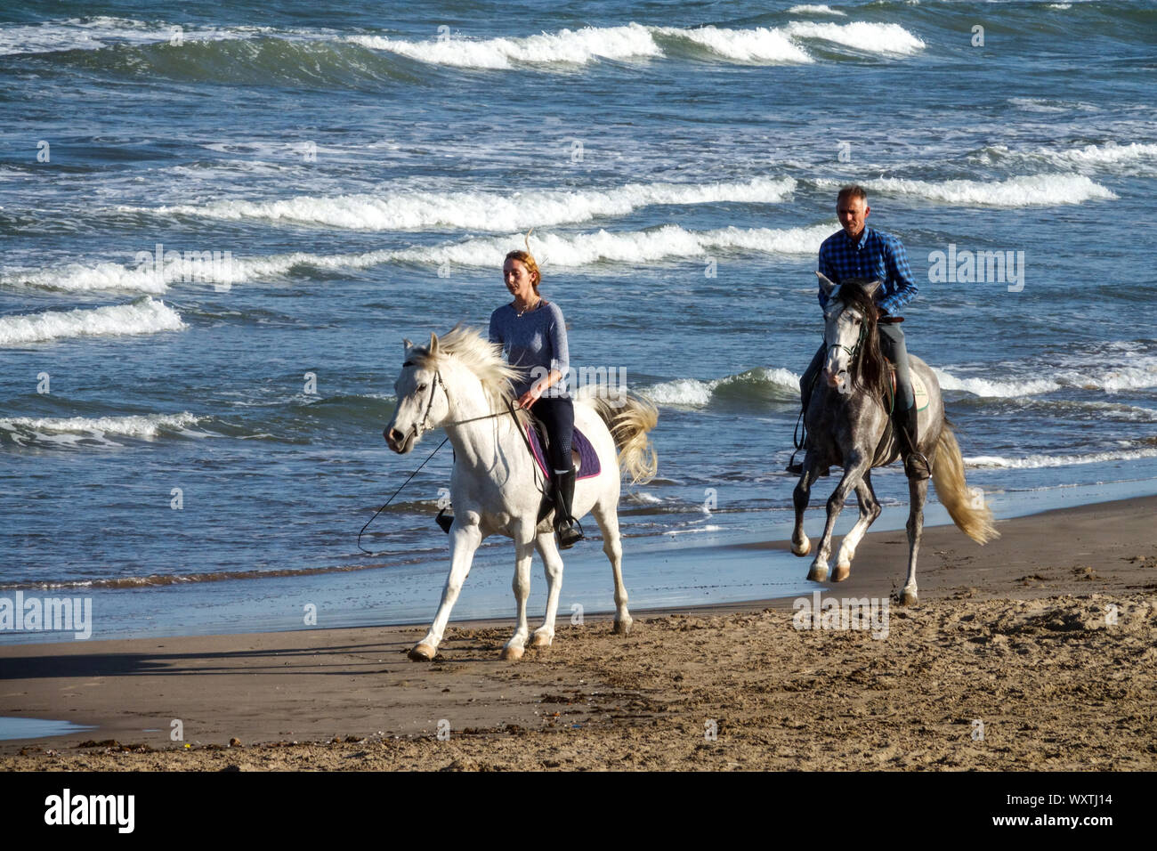L'homme et de la femme de l'équitation sur la plage, Costa Blanca, Espagne Banque D'Images