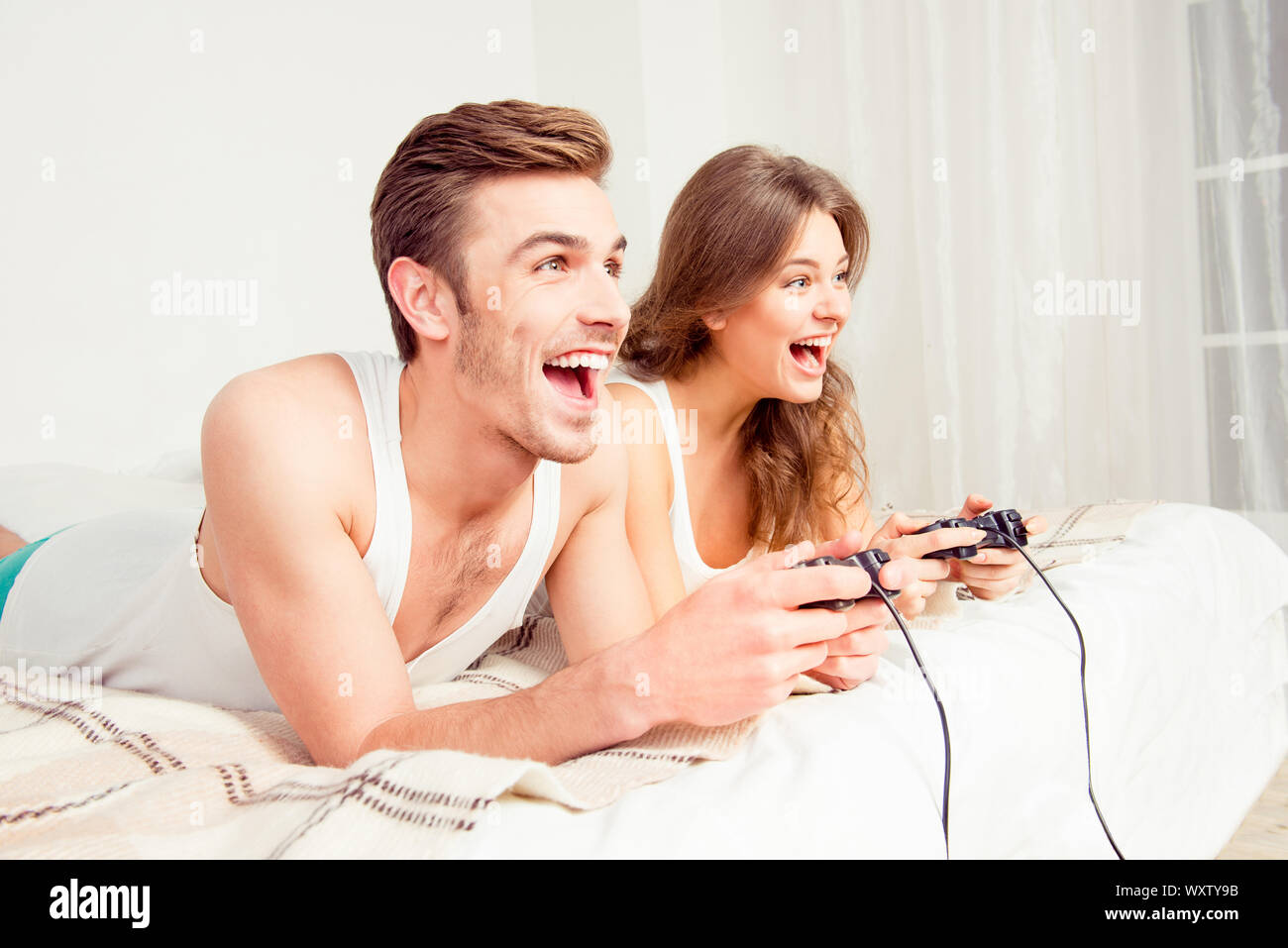 Cheerful couple amoureux à jouer aux jeux vidéo avec une manette sur le lit  Photo Stock - Alamy