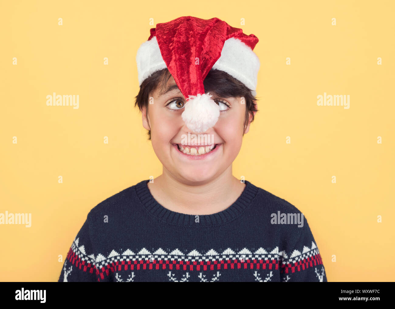 Enfant drôle Wearing Christmas Santa Claus Hat sur fond jaune Banque D'Images