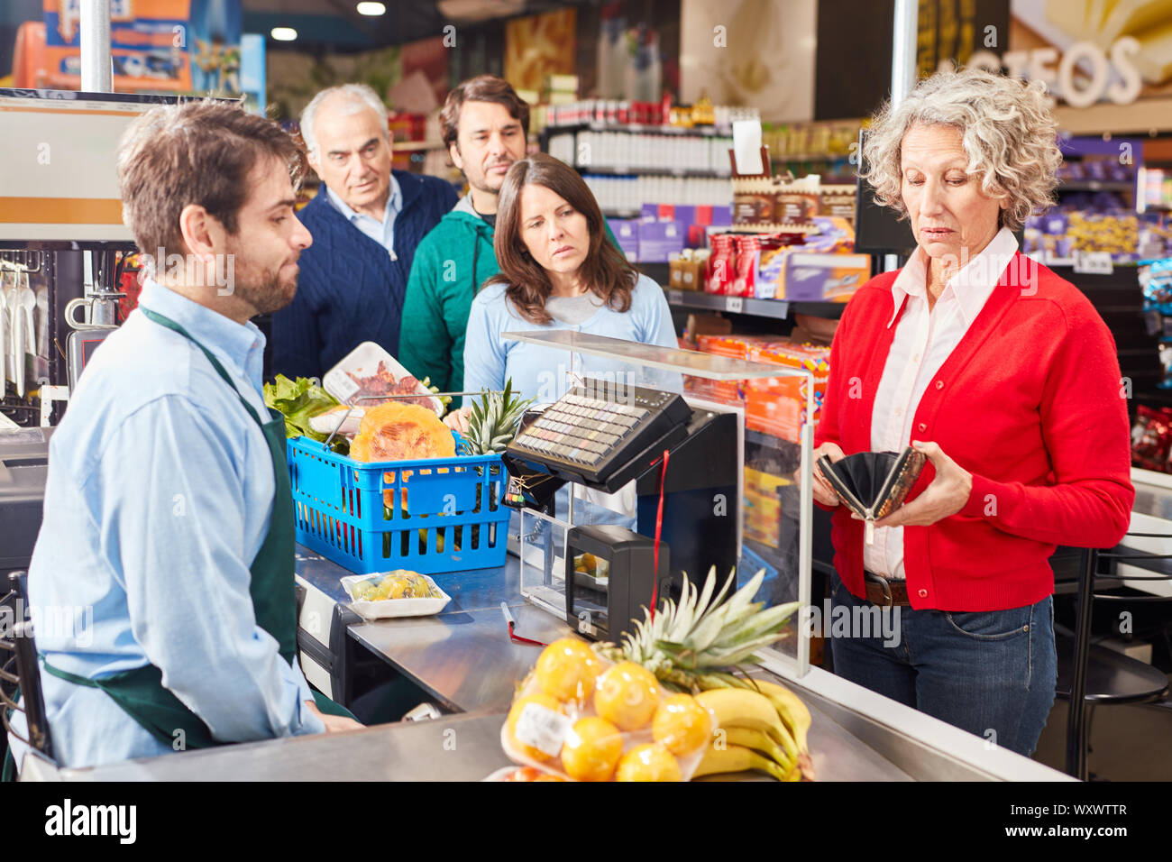 Senior woman de payer la caisse au supermarché cherche dans son portefeuille Banque D'Images