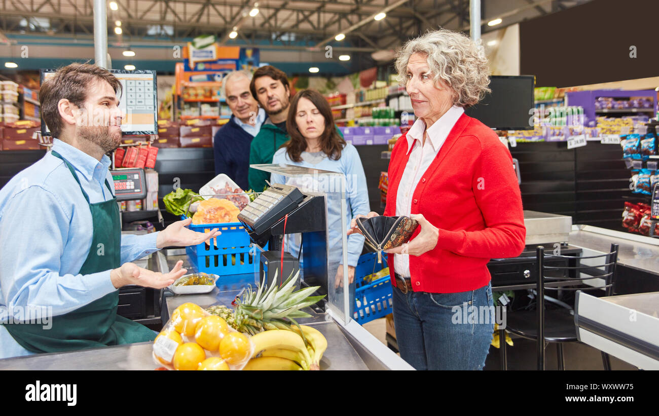 Vieille Femme est à la recherche d'argent pour payer en portefeuille à la caisse du supermarché Banque D'Images