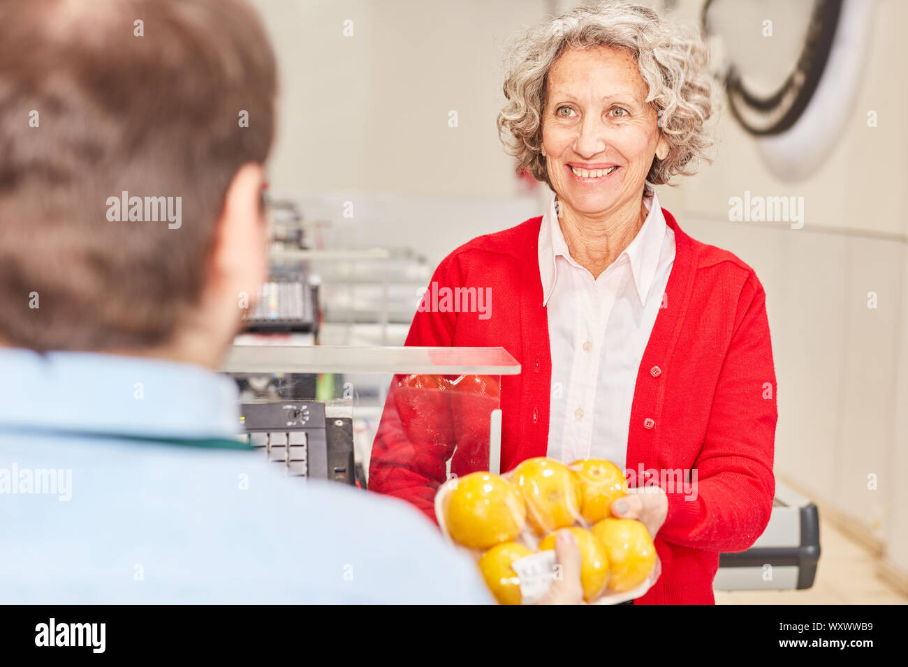 Smiling senior femme comme un client dans le supermarché à la caisse en payant Banque D'Images
