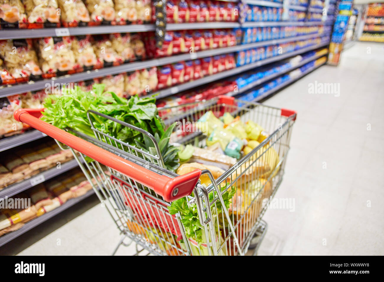 Panier complet avec de la nourriture dans l'allée du supermarché Banque D'Images