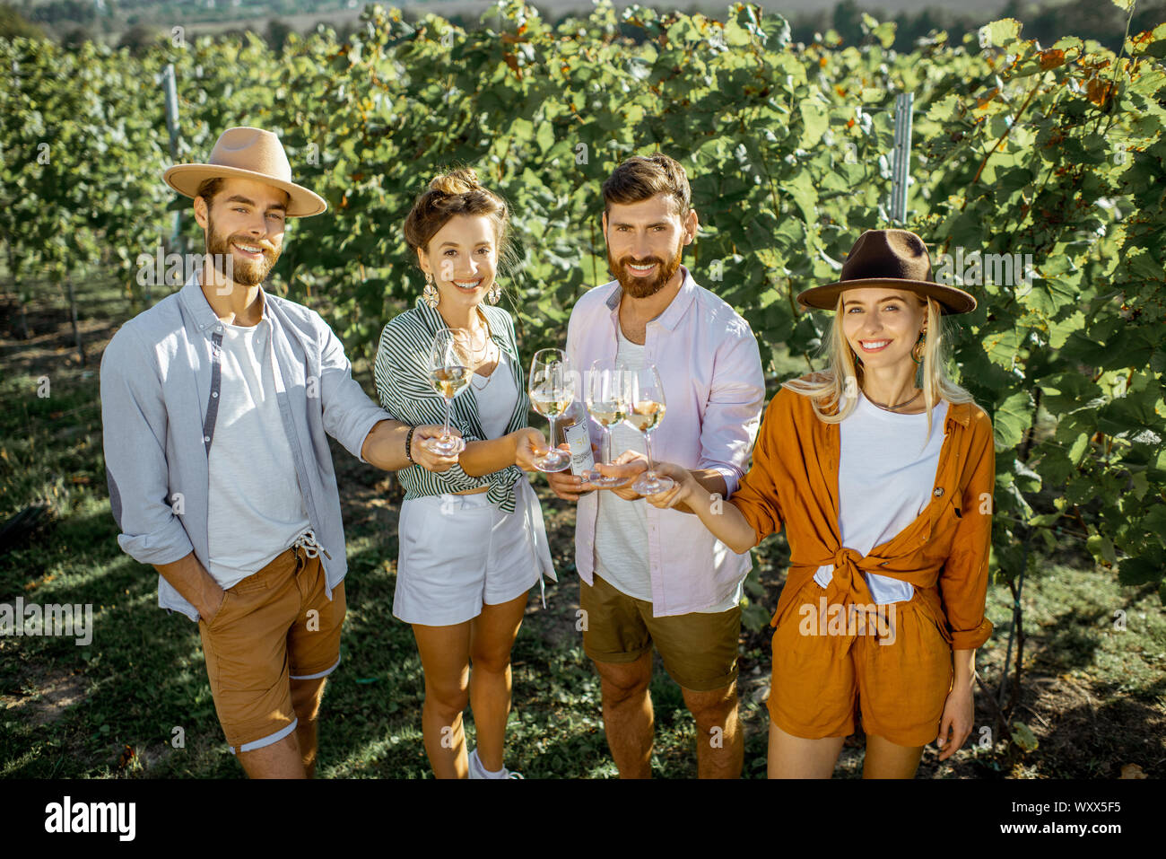 Portrait d'une jeune sylish friends standing avec des verres à vin, passer du temps ensemble sur le vignoble sur un matin d'été ensoleillé Banque D'Images