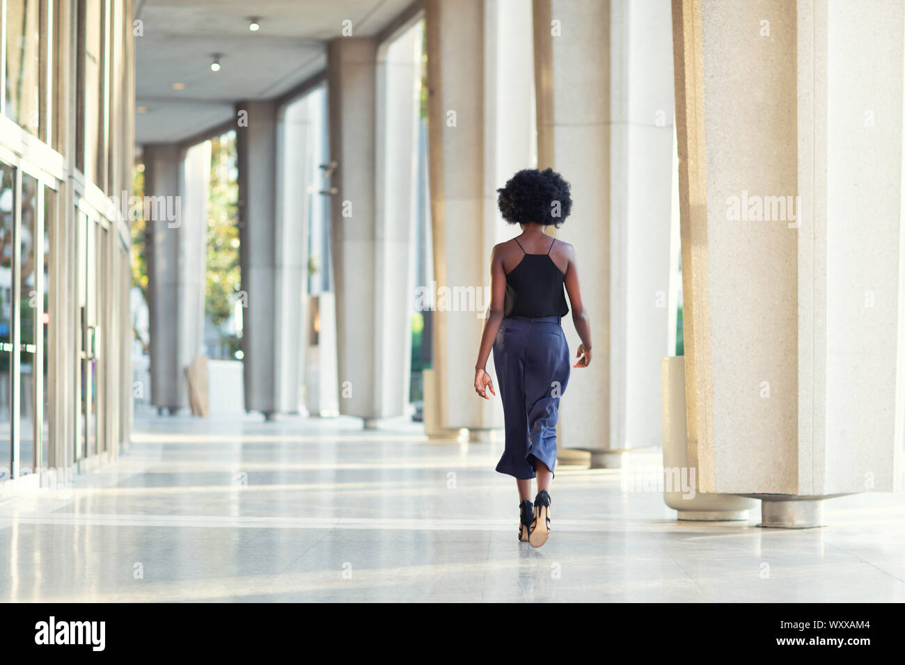 Une jeune femme à la mode de marche loin de l'appareil photo Banque D'Images