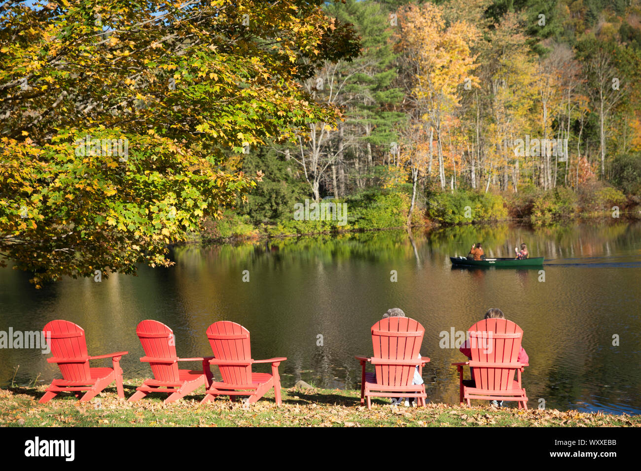 Les touristes à Muskoka chaises, aussi connus comme des chaises Adirondack et canot de sauvetage sur le lac près de Ludlow dans le Vermont, New England, USA Banque D'Images