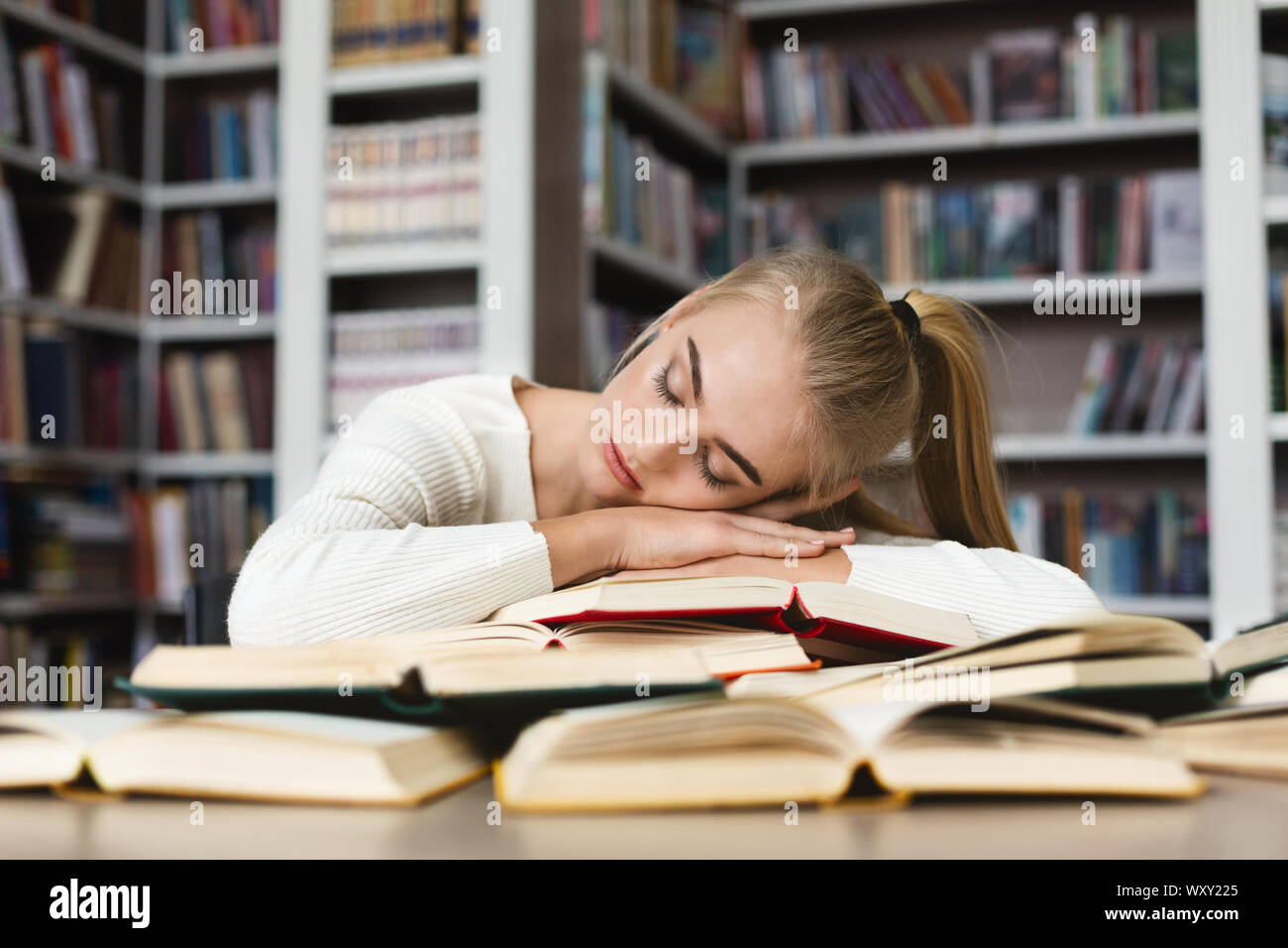 Jeune fille blonde avoir pan pendant ses études à library Banque D'Images